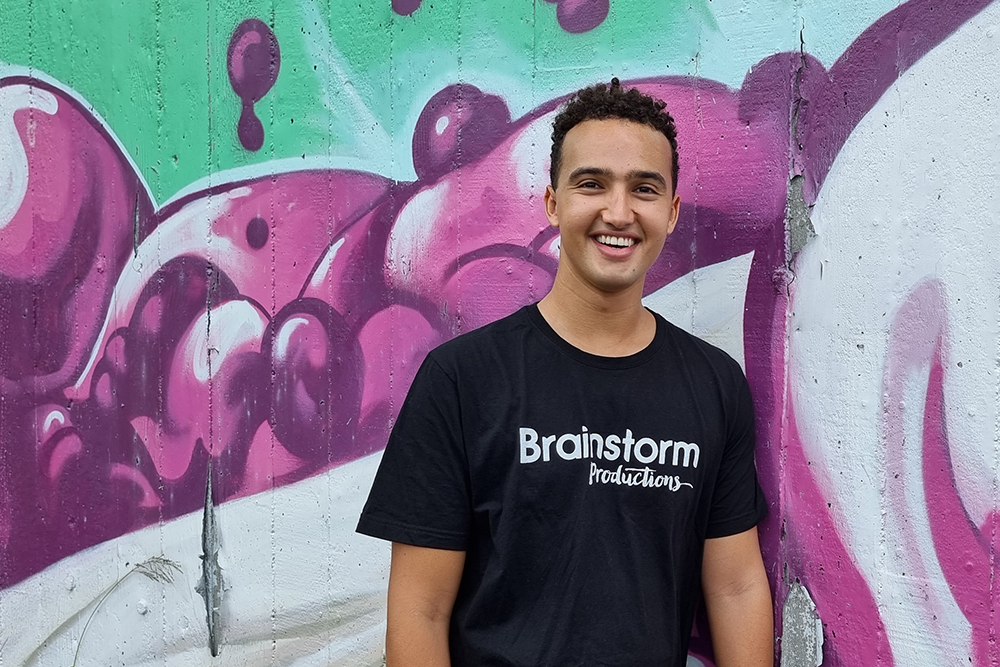 Brisbane based Brainstorm Productions actor Raph smiling for the camera in front of a brightly coloured mural