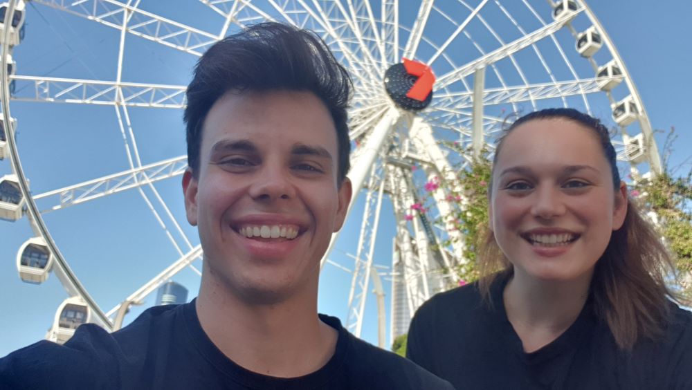 Two Brainstorm Productions actors smiling in front of the Brisbane Wheel between educational theatre performances in Brisbane schools