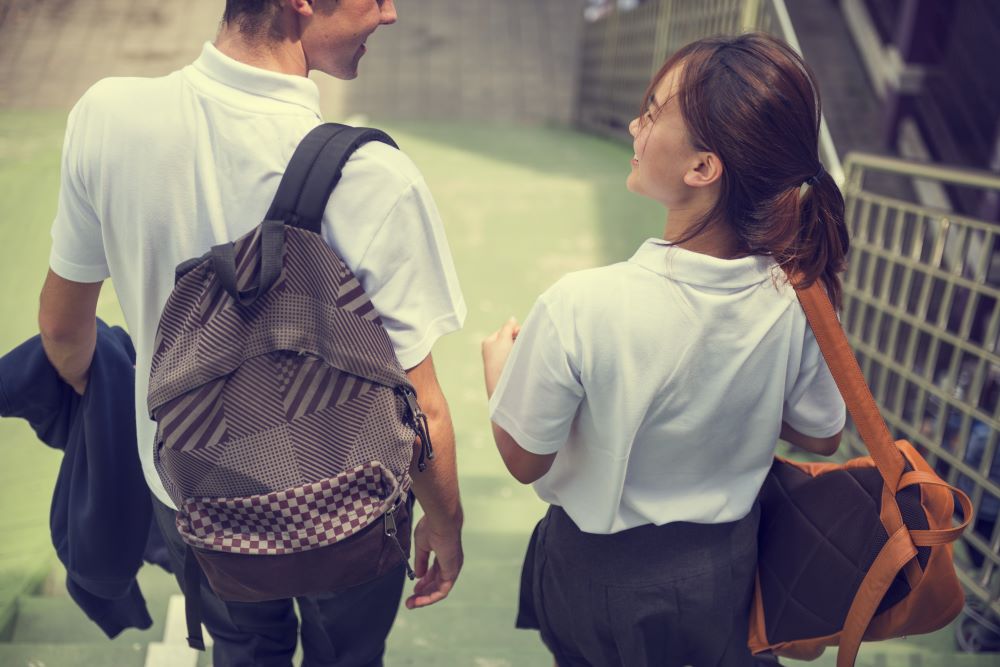 Two high school students walking down stairs talking