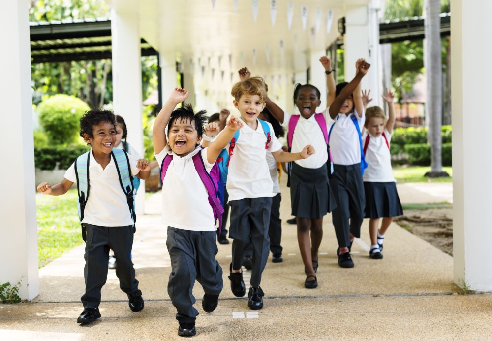 A group of happy primary school students walking towards the camera in a school