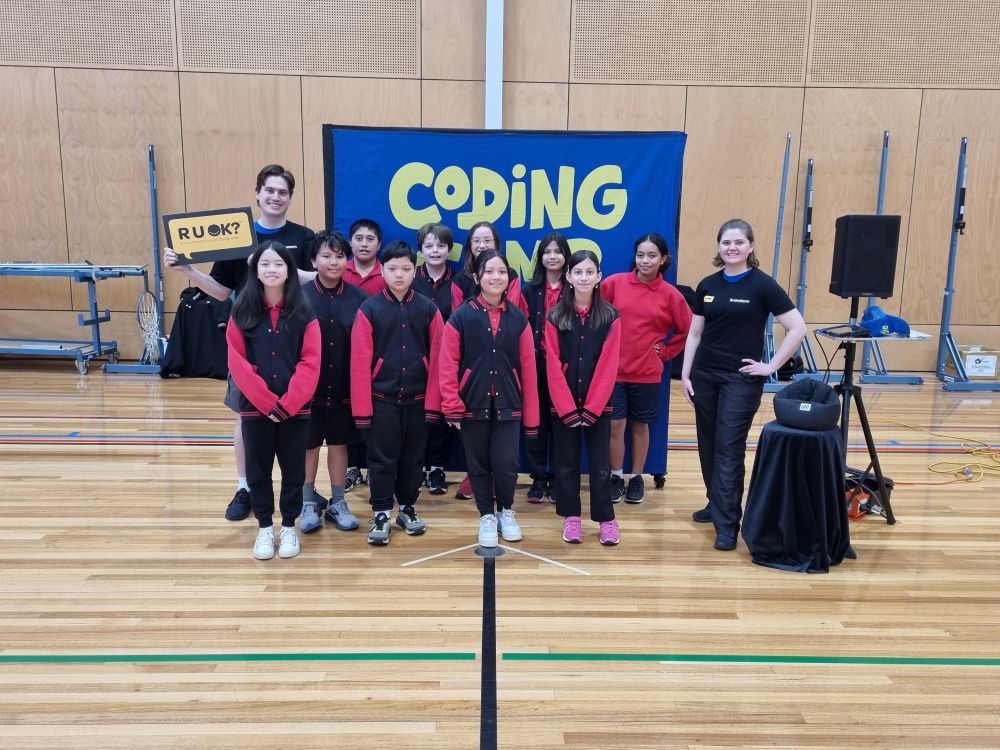 Two Brainstorm Productions actors, Bailee and James, are standing with a group of Victorian high school students on R U OK?Day 2023