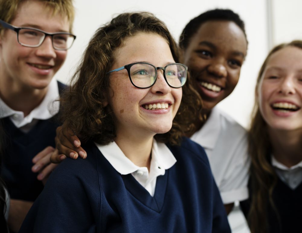 A group of high school students are looking at something and smiling